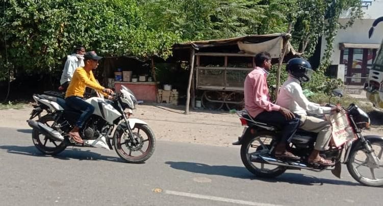 बिना हेलमेट सड़क पर फर्राटा भरता बाइक सवार युवक। 