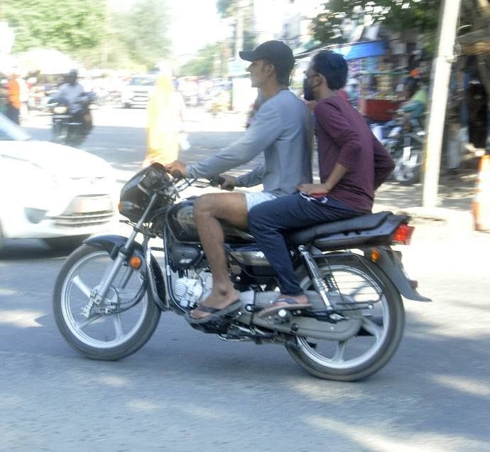 बगैर हेलमेट और मास्क के सड़क पर गुजरते बाइक सवार।