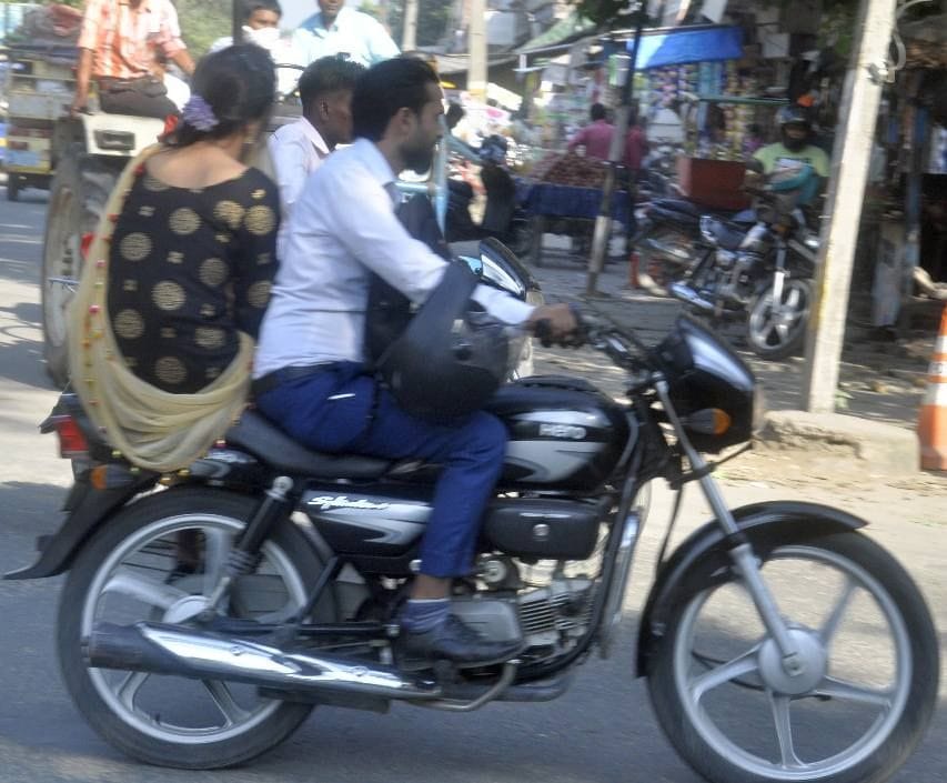 सड़क सुरक्षा सप्ताह के पहले दिन हेलमेट को लगाने की वजह हाथ में पकड़कर जाता बाइक सवार।