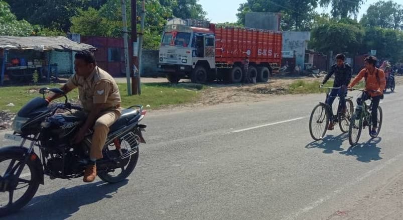 छतरी चौराहे की ओर बिना मास्क और बिना हेलमेट लगाए जाता पुलिस कर्मी।