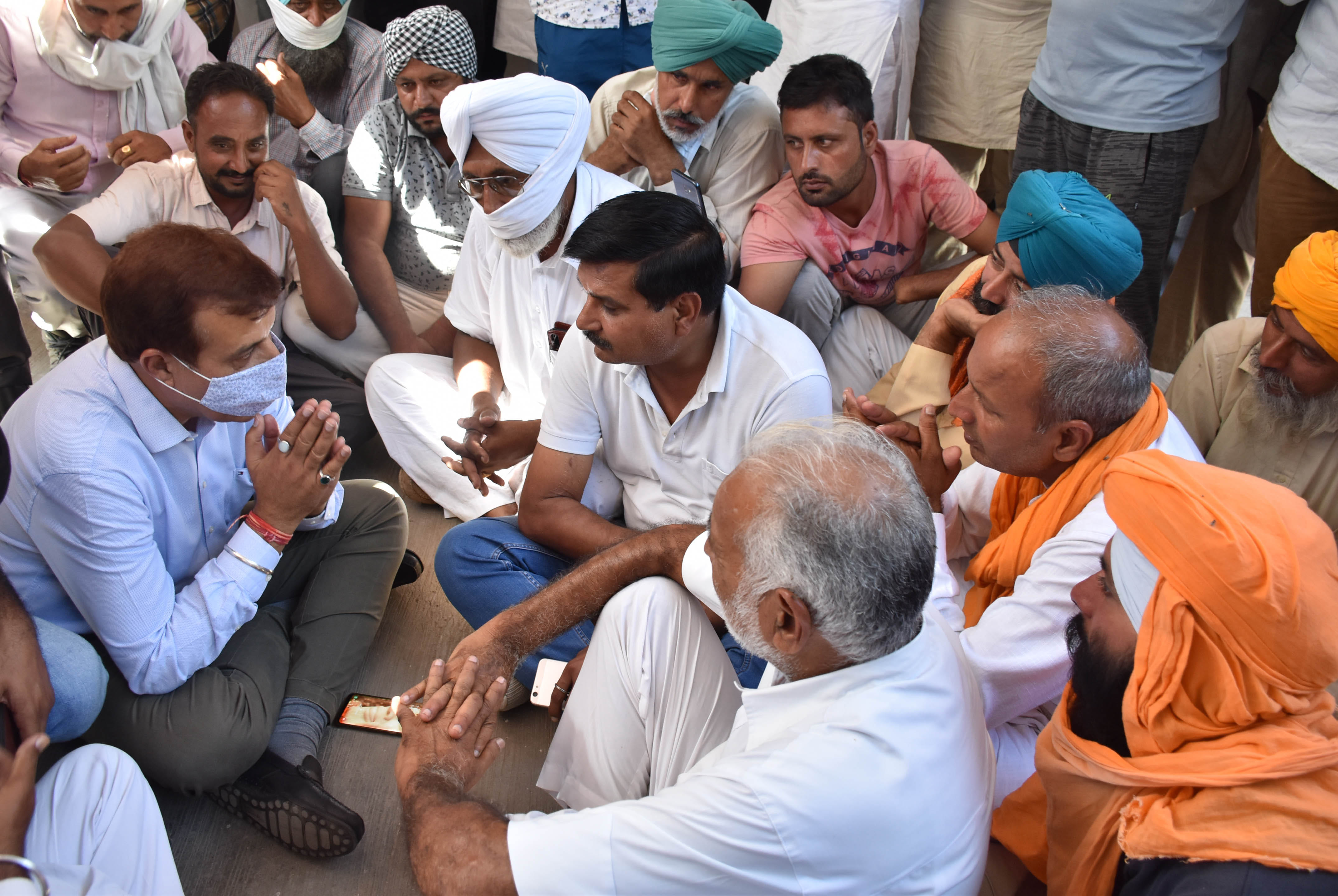 धरने पर बैठे किसानों को हाथ जोड़कर आश्वासन देते सीएमईओ आरके बेनिवाल।