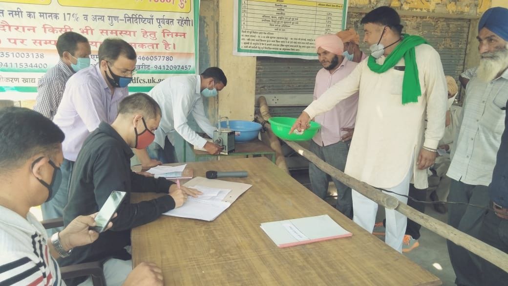खटीमा मंडी में किसानों के धान की नमी मापते मंडी अधिकारी।
