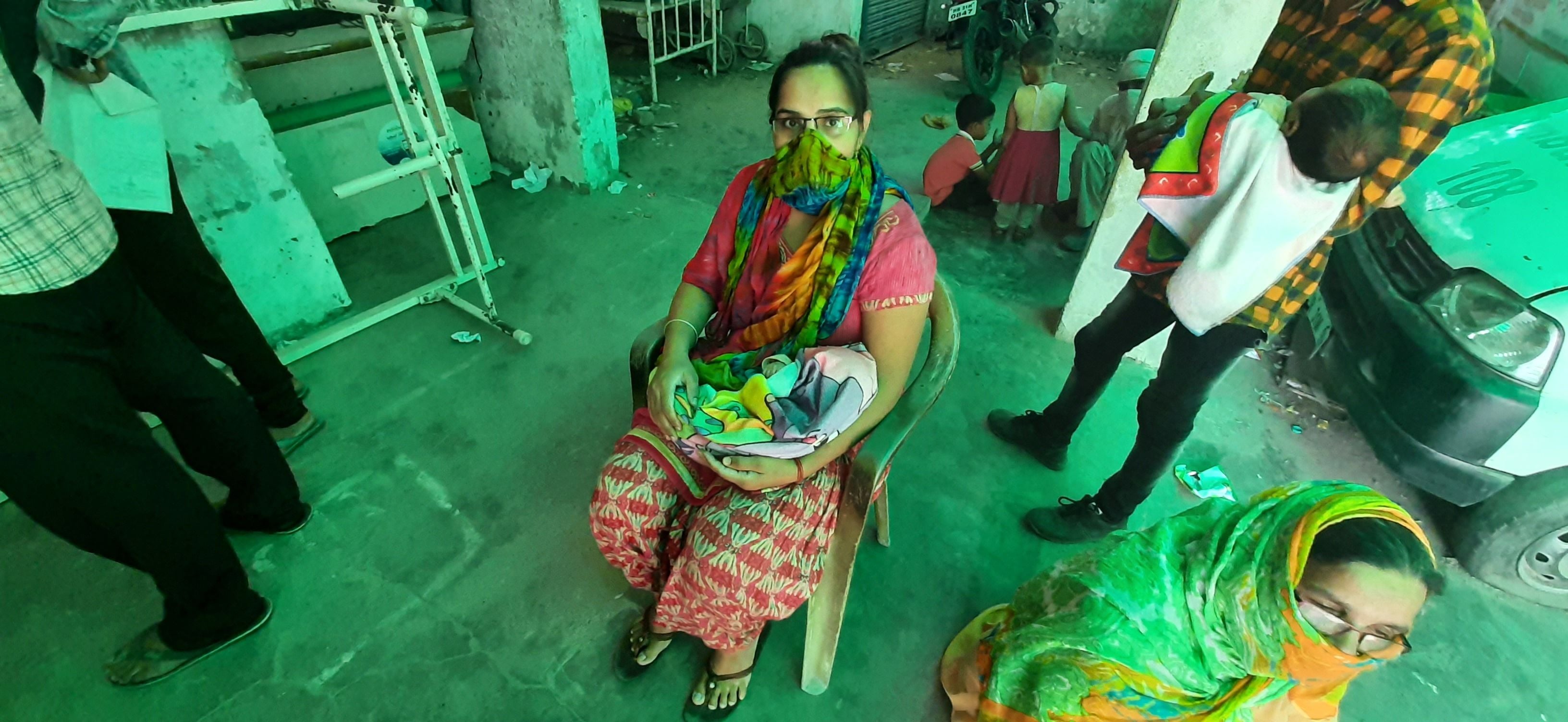 अपनी बारी की इंतजार में अपने नवजात बच्चे को लेकर बैठी एक महिला। अपनी बारी की इंतजार में अपने नवजात बच्चे को लेकर बैठी एक महिला।