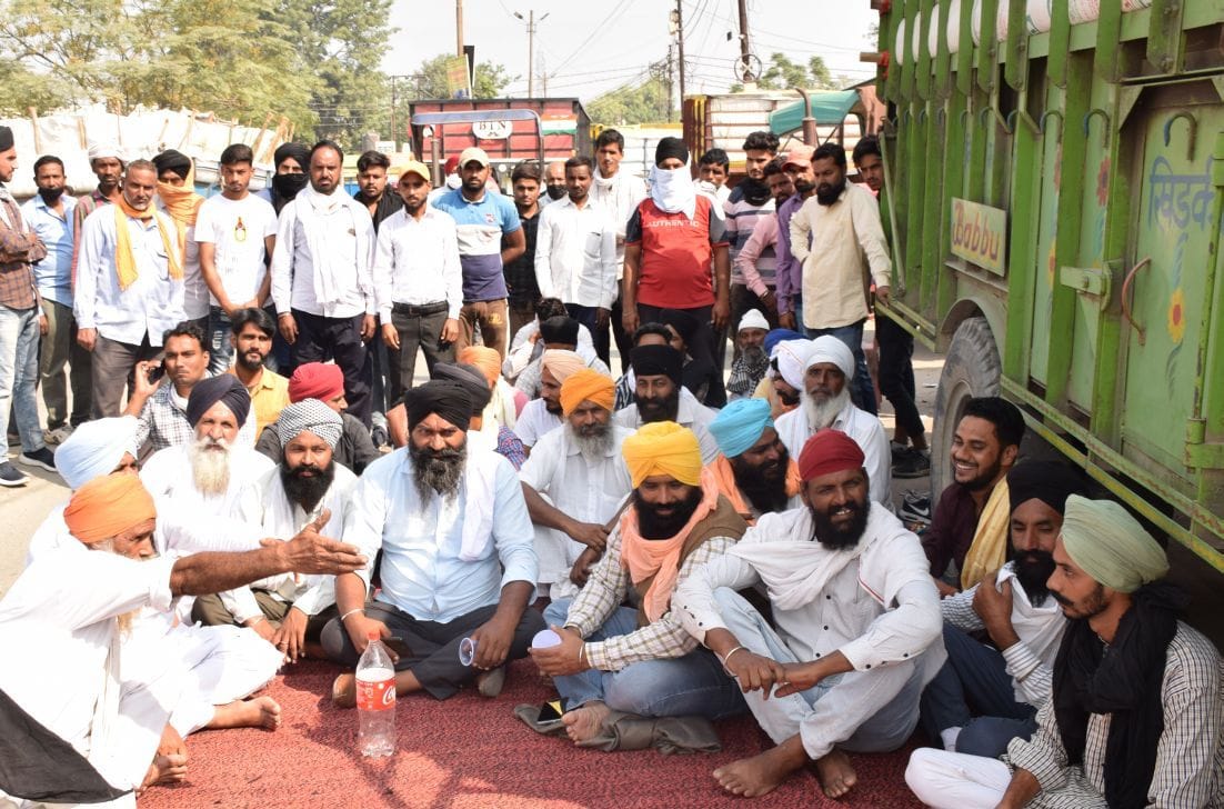 रुद्रपुर गल्ला मंडी मार्ग पर धरना देते किसान। रुद्रपुर गल्ला मंडी मार्ग पर धरना देते किसान।