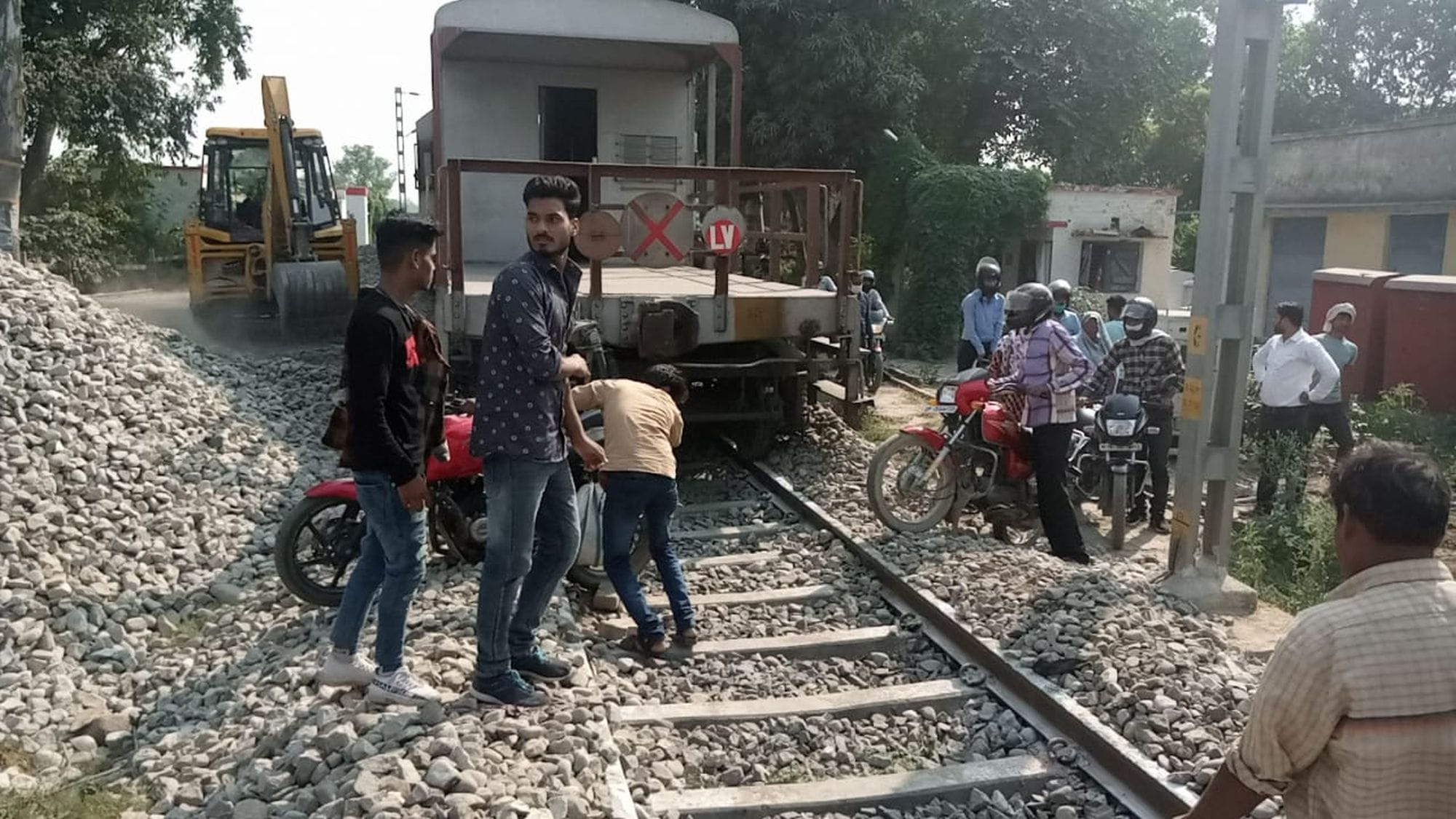मालगाड़ी के पटरी से उतरने पर ट्रैक से बाइकेंनिकालते लोग। 