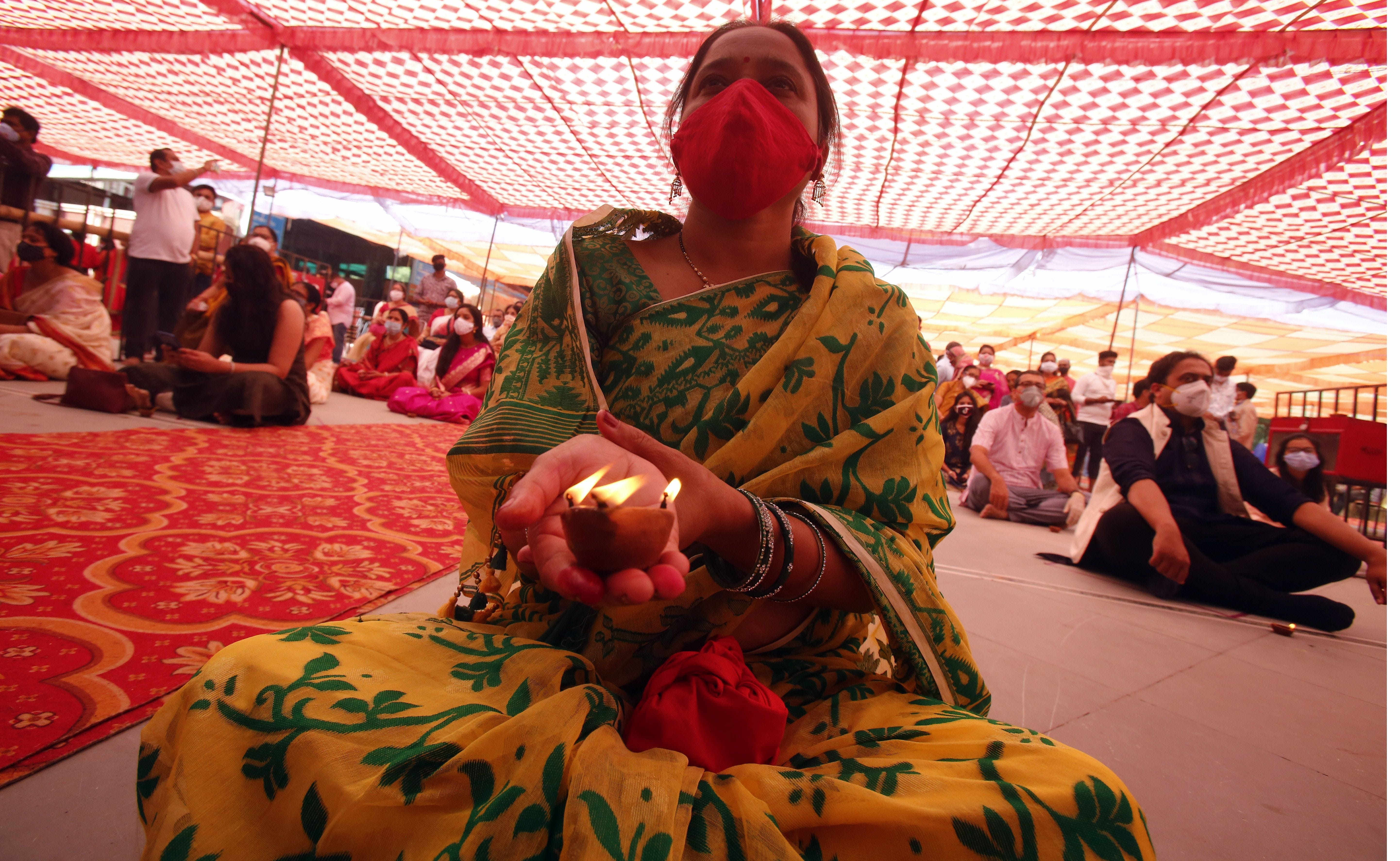 हथेली पर दीपक जलाकर पूजा करती महिला। हथेली पर दीपक जलाकर पूजा करती महिला।