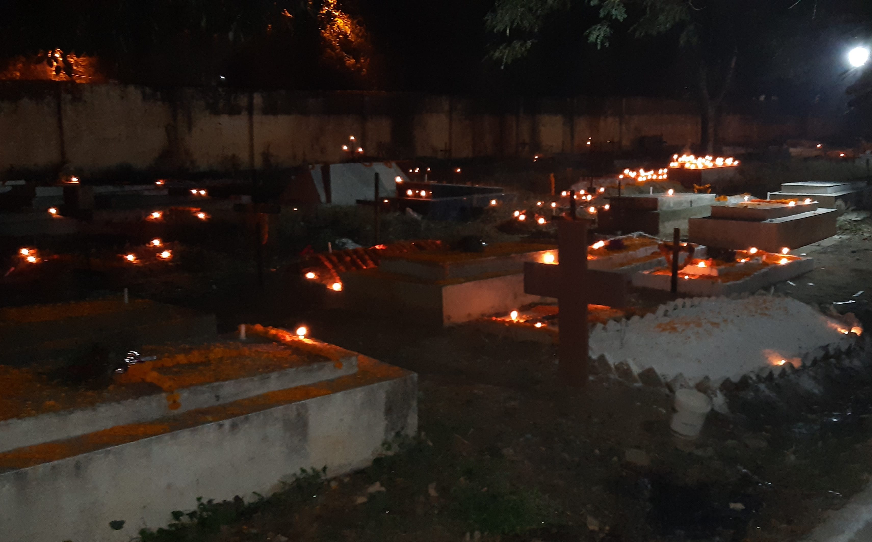 रात के समय कब्रों पर जलाई गई मोमबत्तियों से जगमगता कब्रिस्तान
