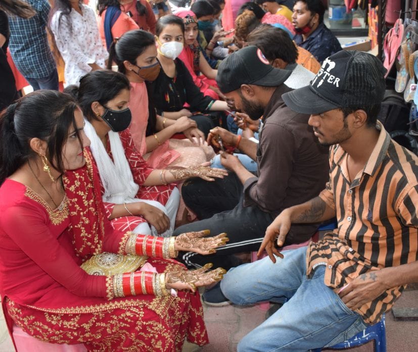 रुद्रपुर विधवानी बाजार में हाथों में मेहंदी लगवाती महिलाएं। रुद्रपुर विधवानी बाजार में हाथों में मेहंदी लगवाती महिलाएं।