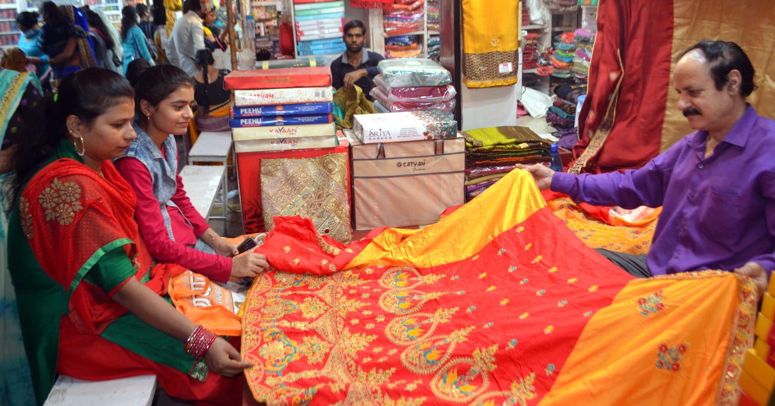 पूजा में शामिल होने के लिए लाल रंगी साड़ी खरीदती महिला पूजा में शामिल होने के लिए लाल रंगी साड़ी खरीदती महिला