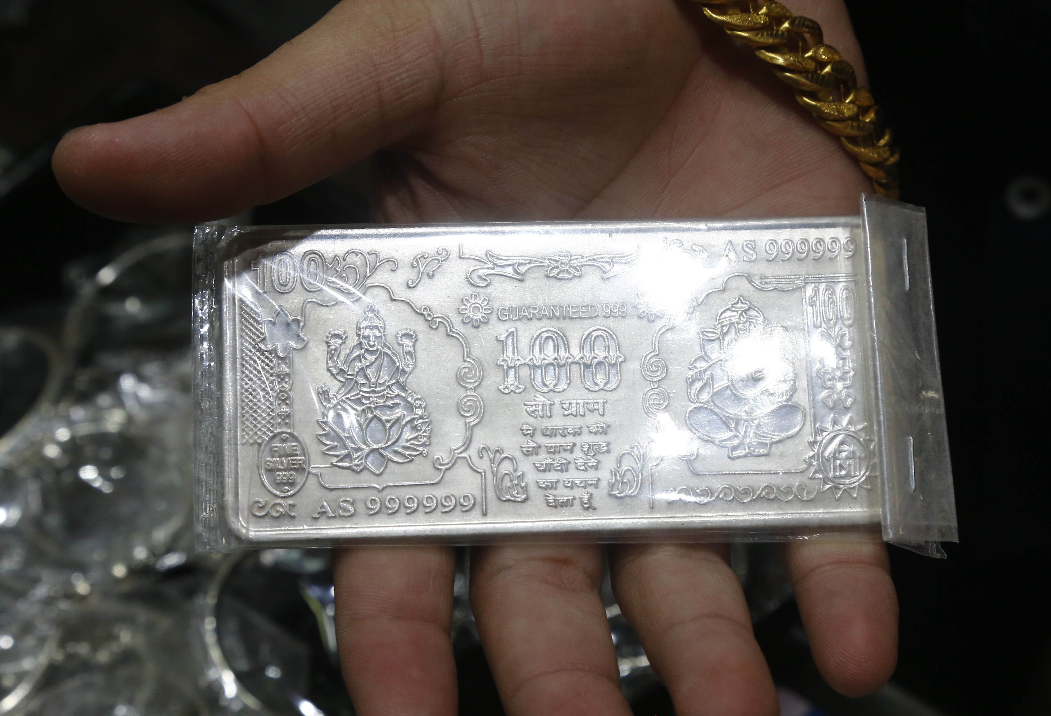 100 रुपये के नोट जैसी बनी चांदी दिखाता दुकानदार।