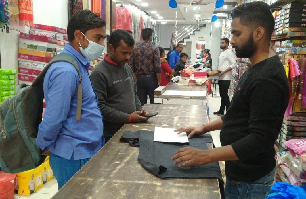 कपड़े की दुकान पर खरीदारी करते लोग। कपड़े की दुकान पर खरीदारी करते लोग।