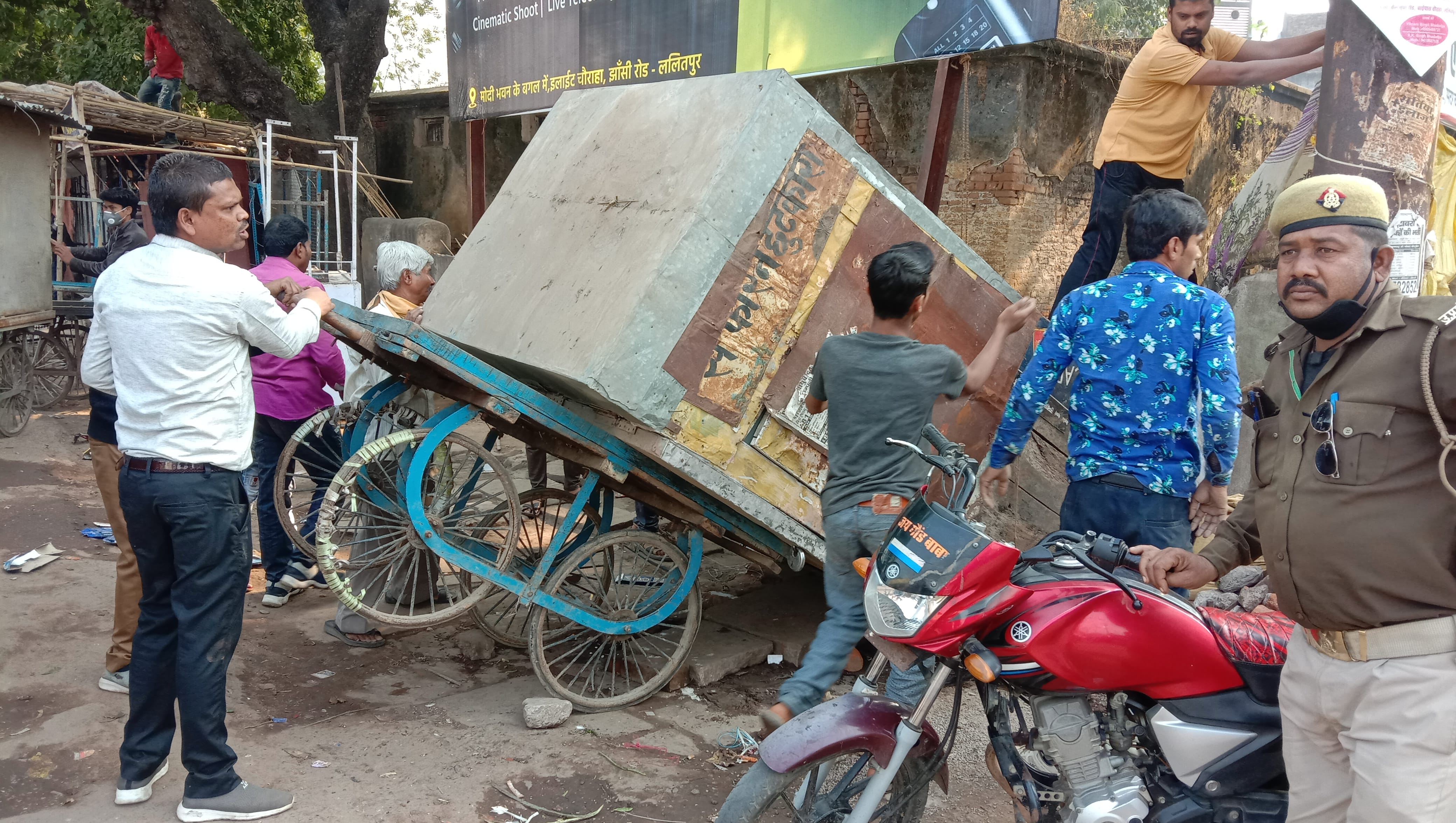 अपनी गुमटी को हाथ ठेले पर ले जाते लोग अपनी गुमटी को हाथ ठेले पर ले जाते लोग