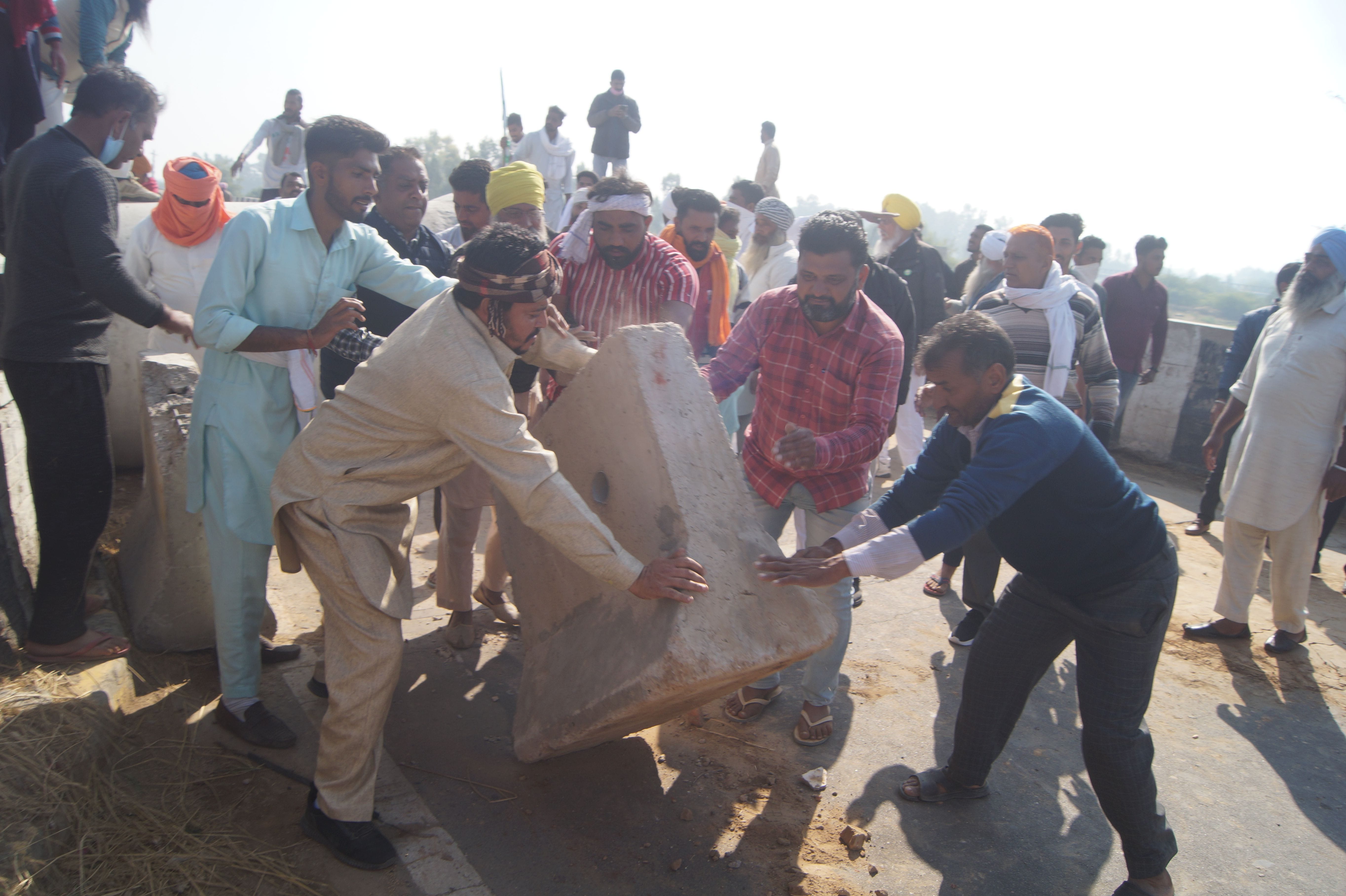 घग्गर पुल पर प्रशासन द्वारा लगाए गए सीमेंट बैरिकेड हटाते किसान। घग्गर पुल पर प्रशासन द्वारा लगाए गए सीमेंट बैरिकेड हटाते किसान।