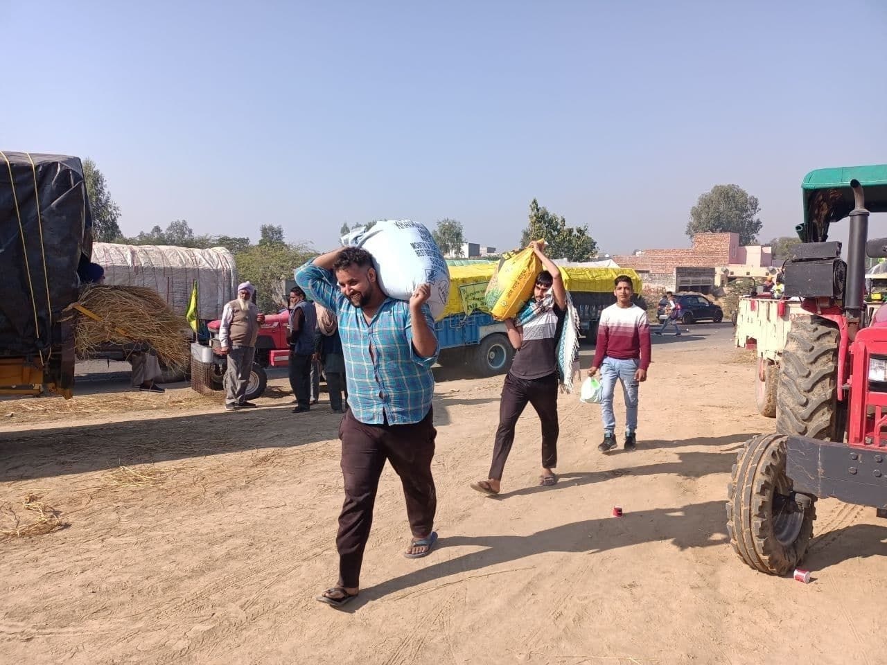 किसानों के ट्रैक्टर में आटे से भरे कट्टे रखने के लिए लेकर जाते पोली गांव के युवा। संवाद किसानों के ट्रैक्टर में आटे से भरे कट्टे रखने के लिए लेकर जाते पोली गांव के युवा। संवाद