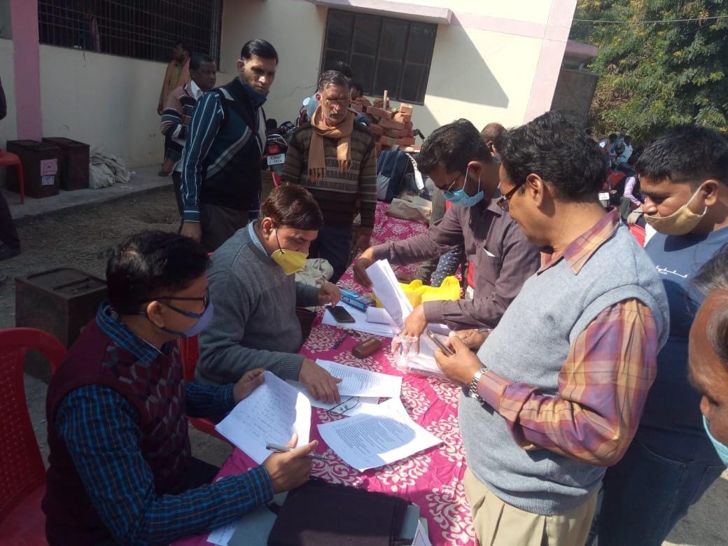 पोलिंग स्टेशन पर डियूटी की जानकारी करते कर्मचारी