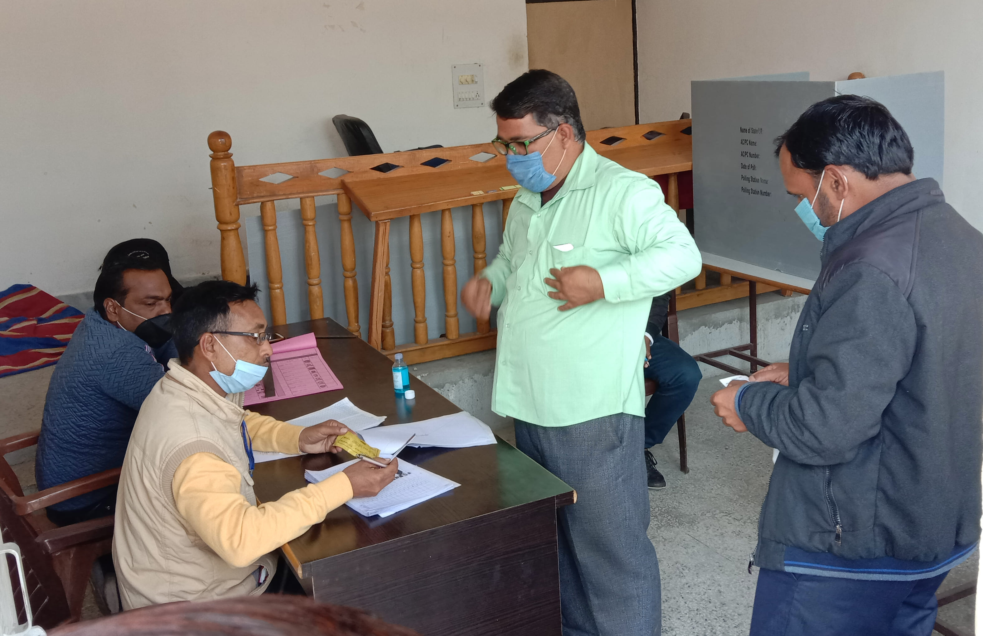 स्नातक एमएलसी चुनाव में मतदाता सूची में मतदाता का नाम देखते अधिकारी