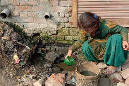 हलालपुर में घर के बाहर खोदे गए गड्ढे से पानी निकालती बच्ची। हलालपुर में घर के बाहर खोदे गए गड्ढे से पानी निकालती बच्ची।
