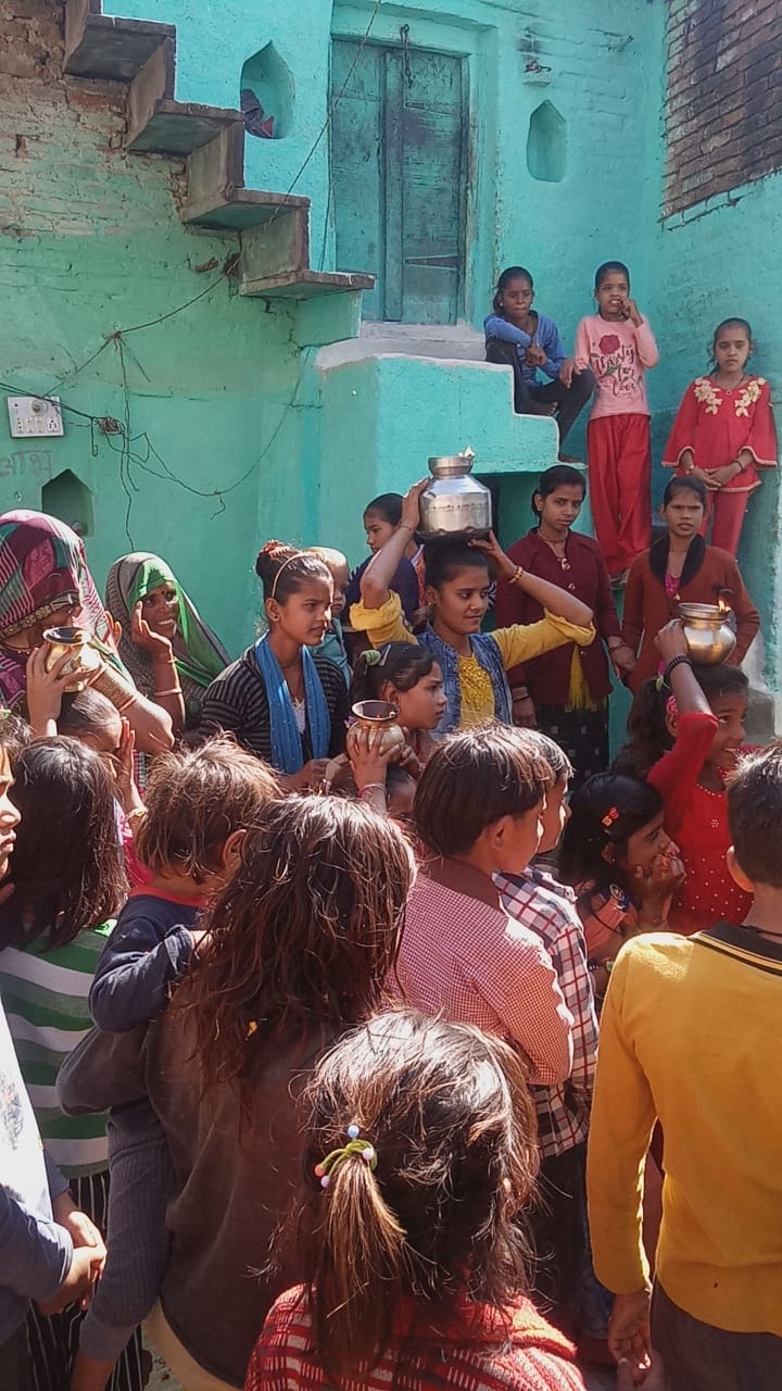 सोनू के स्वागत को सिर पर कलश रखकर खड़ी युवती सोनू के स्वागत को सिर पर कलश रखकर खड़ी युवती