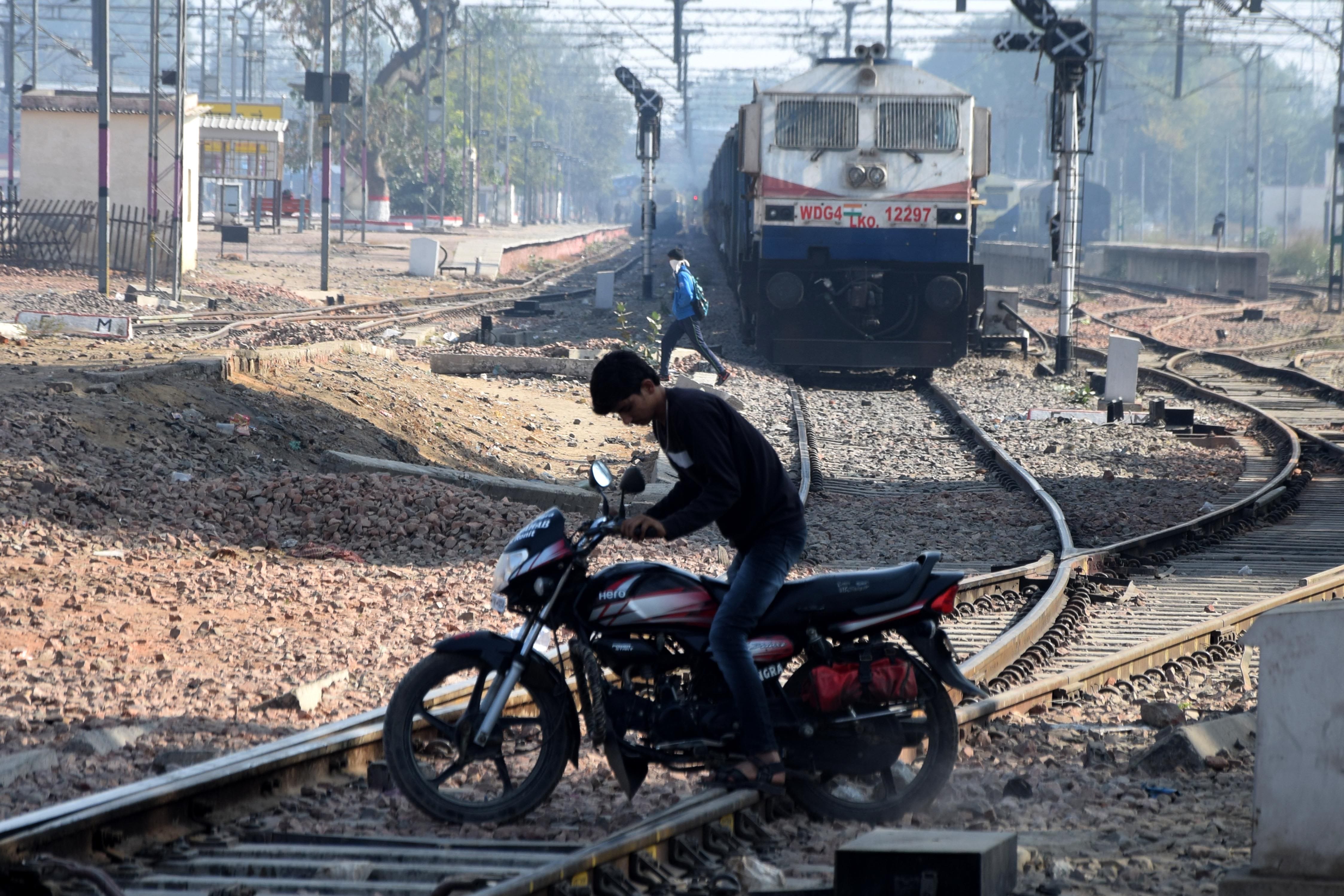 कच्चा बेरी रोड रेलवे क्रासिंग पर फाटक बंद होने पर ट्रेन के आने के समय पटरी को पार कराता बाइक सवार। 