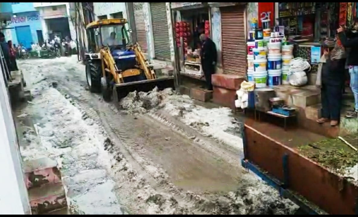 मुजफ्फरनगर जिले के सिसौली में ओलवृष्टि से भरी सड़क को साफ करती जेसीबी।