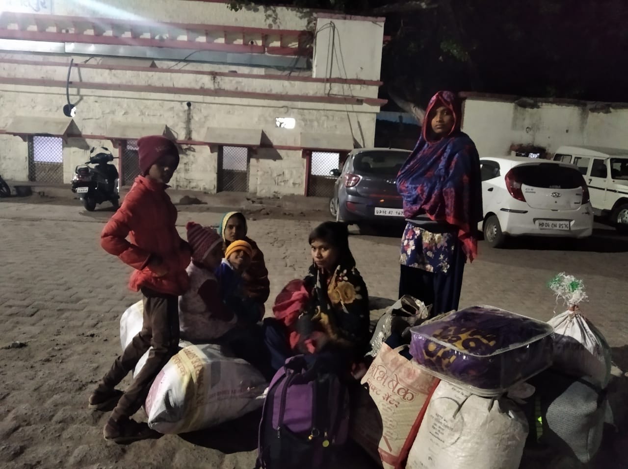 रेलवे स्टेशन के बाहर ठंड में बाहर बैठा परिवार।