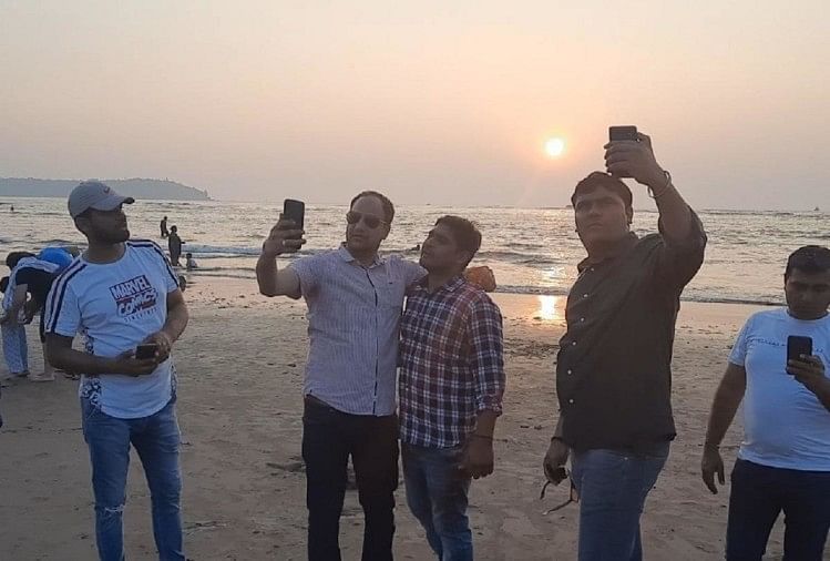 Tourists taking pictures with the sun shining on Miramar Beach in Goa.
