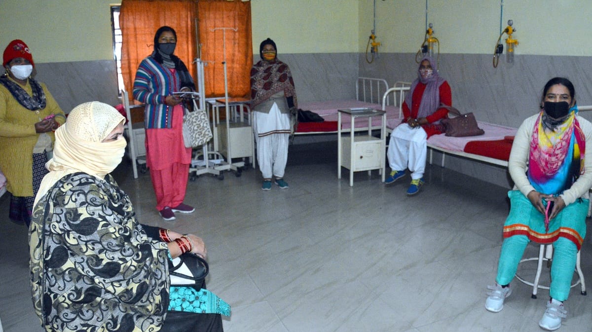 जिला चिकित्सालय में टीकाकरण के बाद प्रतीक्षालय में बैठी स्वास्थकर्मी।