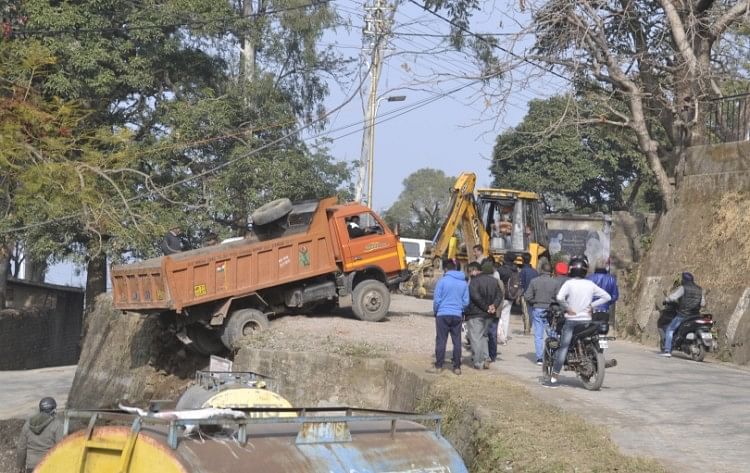 डंगा ढहने से लुढ़का बजरी से लदा ट्रक, कोई हताहत नहीं नाहन में कालीस्थान तालाब के समीप डंगा ढहने से गिरे ट्रक को जीसीबी से निकालते लोग।