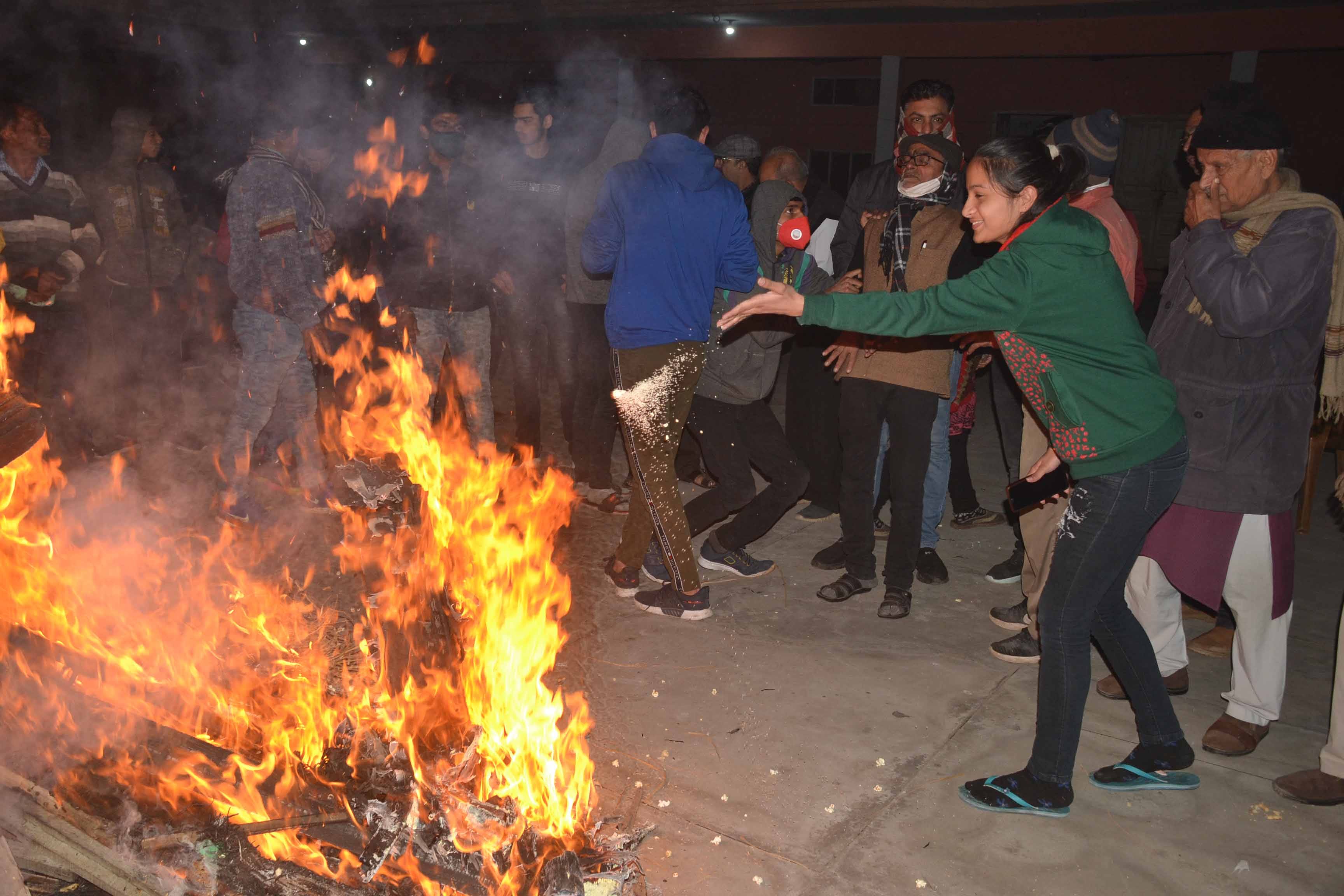 शामली में पंजाबी कॉलोनी स्थित रघुनाथ मंदिर में लोहड़ी में मूंगफली, पोपाकॉर्न डालती युवती।