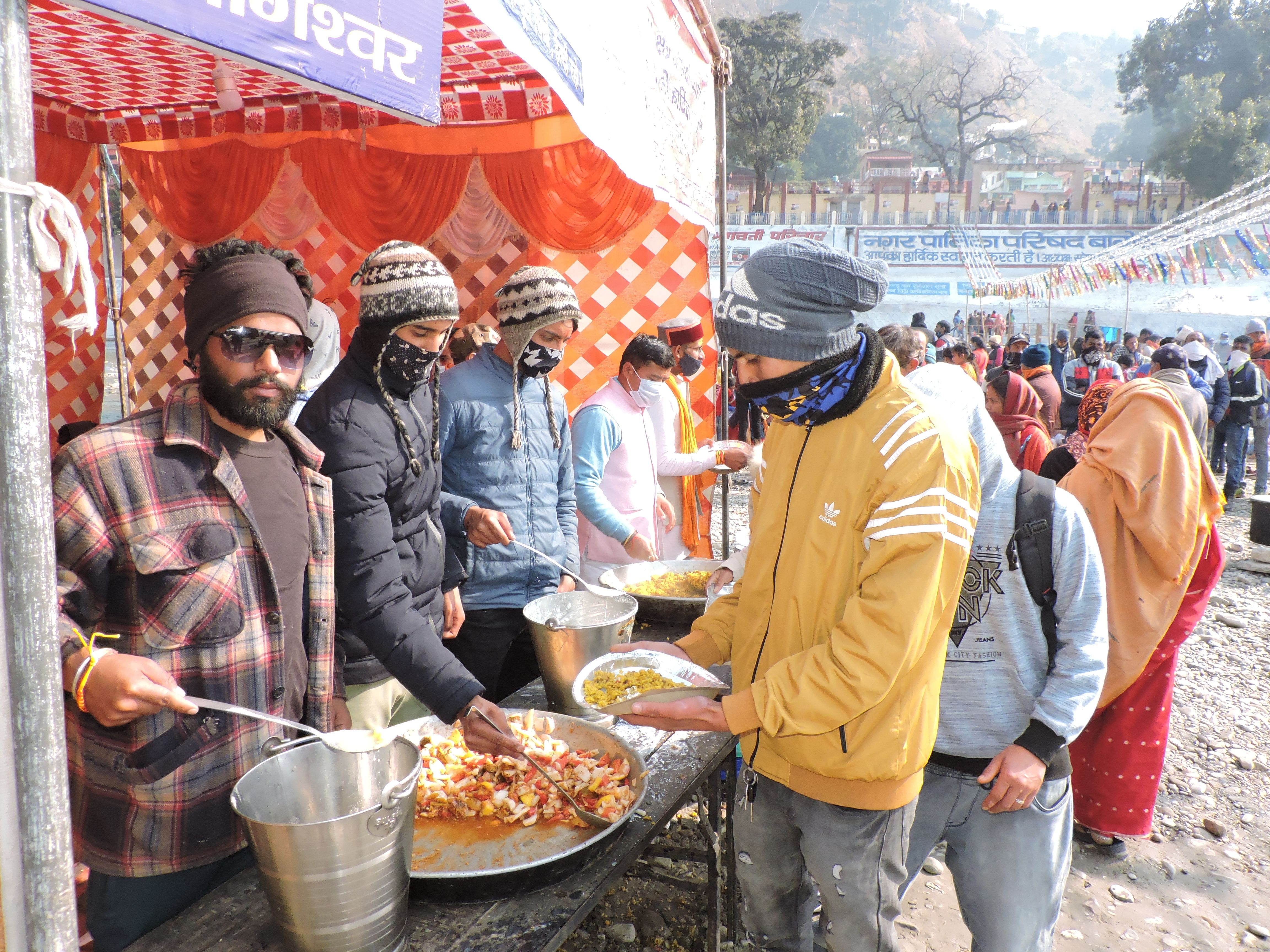 बागेश्वर के सरयू बगड़ में मेलार्थियों को माघी खिचड़ी खिलाते हिजामं कार्यकर्ता। संवाद न्यूज एजे?