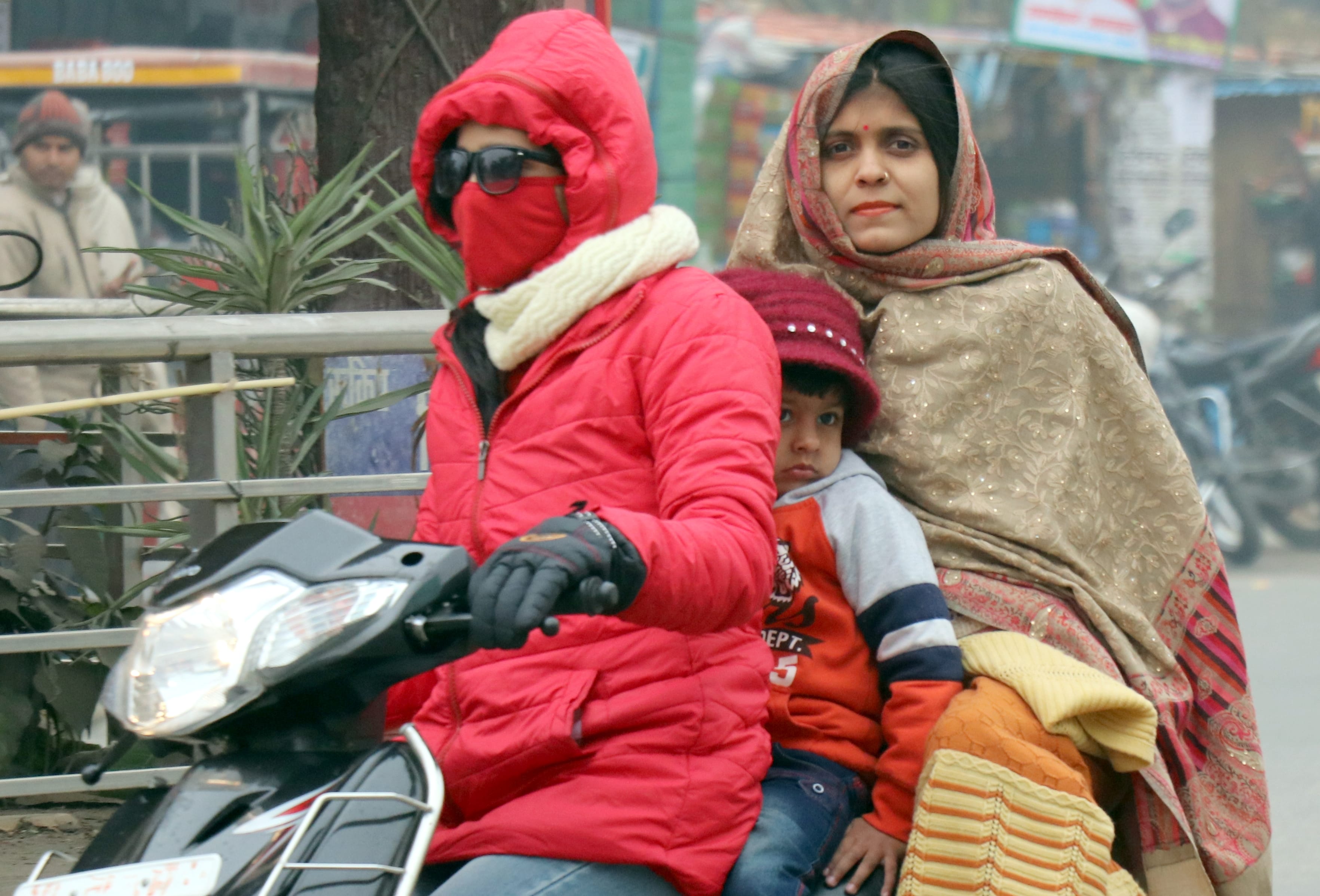 बिजनौर में रविवार को भीषण ठंड में गर्म कपड़ों में लिपटकर जाती स्कूटी सवार।