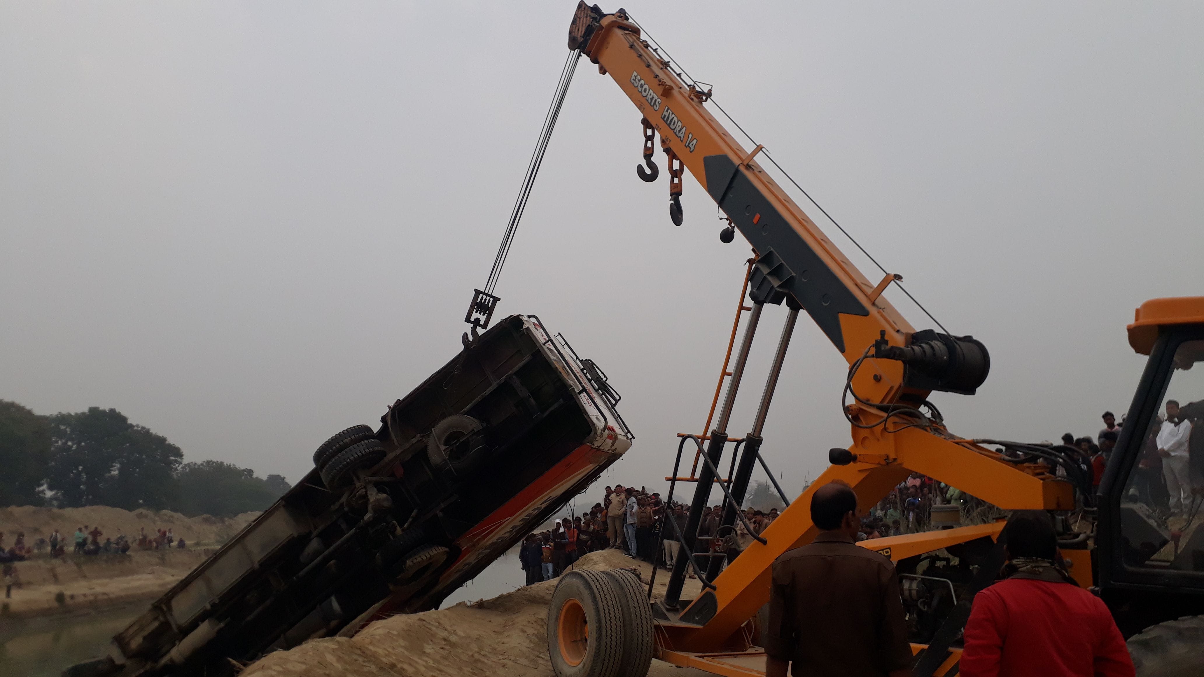 क्रेन से बहर निकाली जाती नहर में पलटी बस। क्रेन से बहर निकाली जाती नहर में पलटी बस।