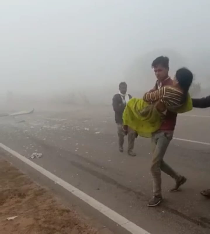 बस दुर्घटना के बाद घायल महिला को ले जाता युवक