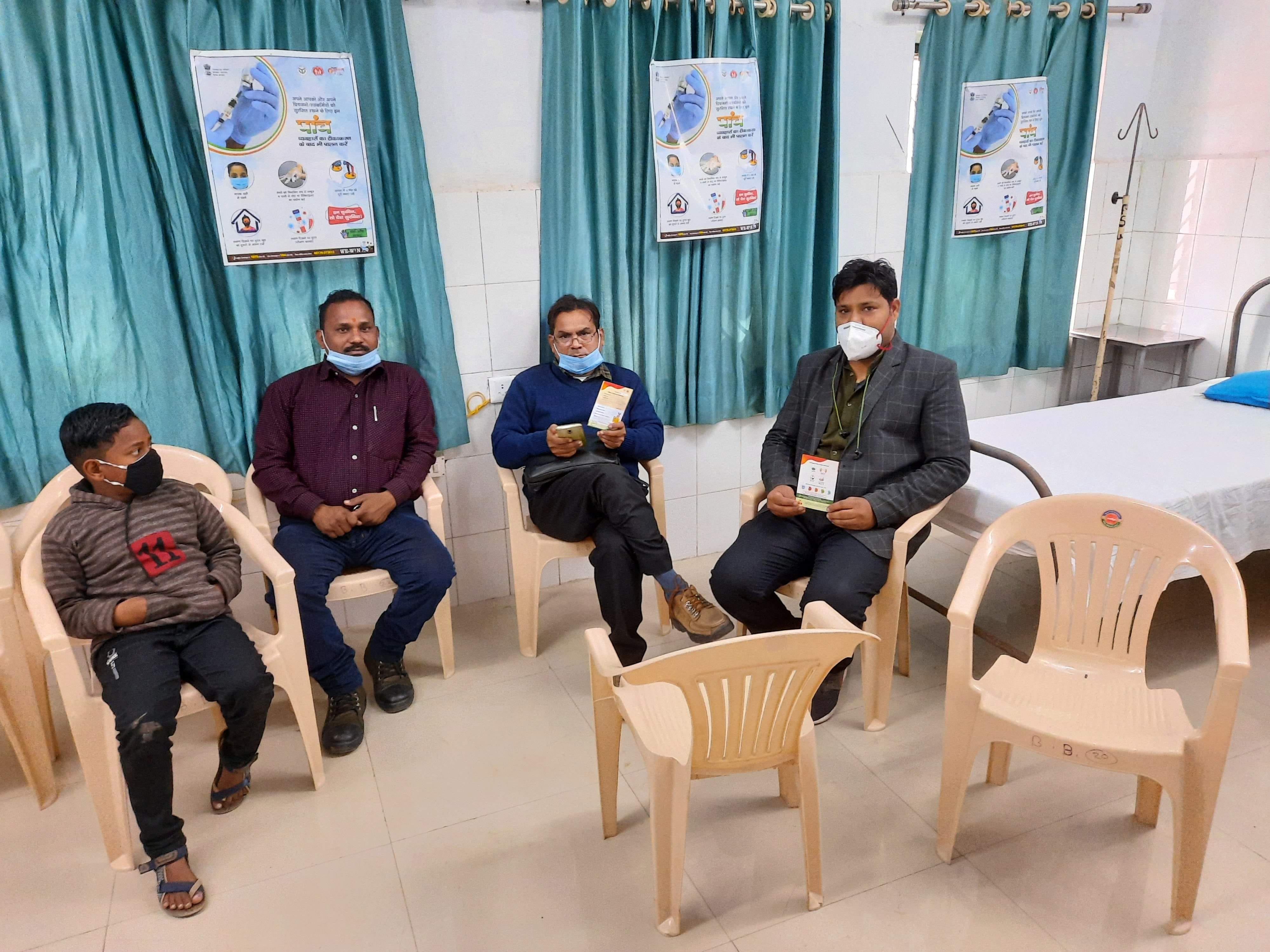 जिला अस्पताल में वैक्सीन लगवाने के बाद कुर्सी पर बैठे स्वास्थ्य कर्मी