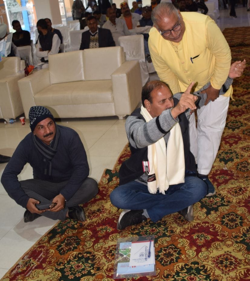 मंच के आगे धरने पर बैठे प्रतिनिधि को उठाते लोग। मंच के आगे धरने पर बैठे प्रतिनिधि को उठाते लोग।