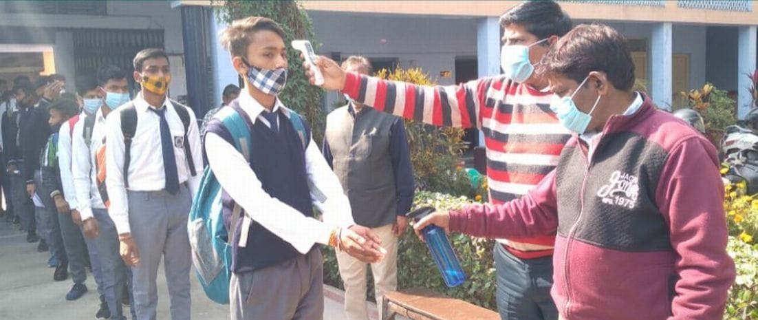 काशीपुर उदयराज हिंदु इंटर कॉलेज में गेट पर छात्र की थर्मल स्केनिंग करते स्कूल कर्मचारी।