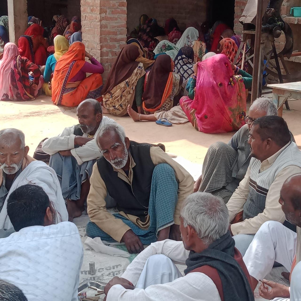 मृतक के घर के बाहर बैठे गमगीन लोग मृतक के घर के बाहर बैठे गमगीन लोग