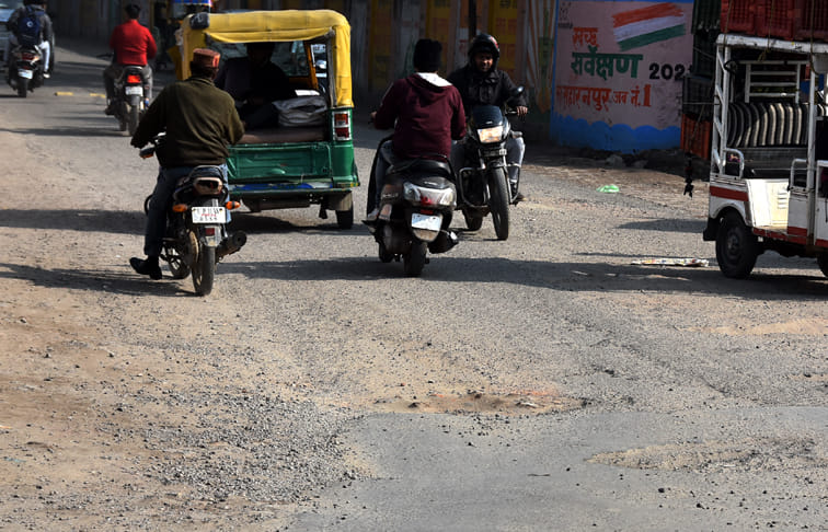 स्टेडियम रोड़ पर टूटी सड़क से गुजरते वाहन स्टेडियम रोड़ पर टूटी सड़क से गुजरते वाहन