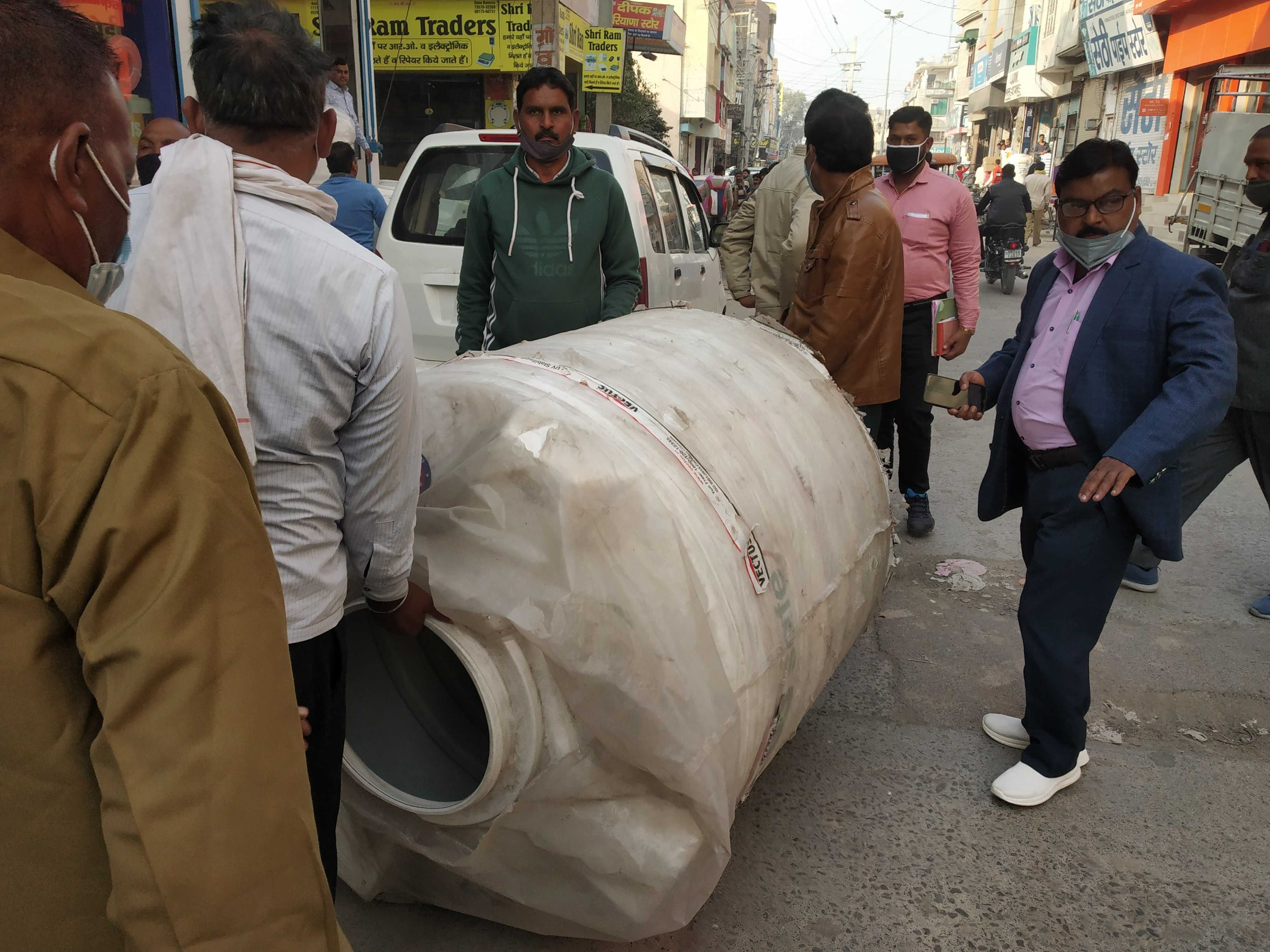बाजार में दुकानों के बाहर पड़ी पानी की टंकी को जब्त करते नप कर्मी। बाजार में दुकानों के बाहर पड़ी पानी की टंकी को जब्त करते नप कर्मी।