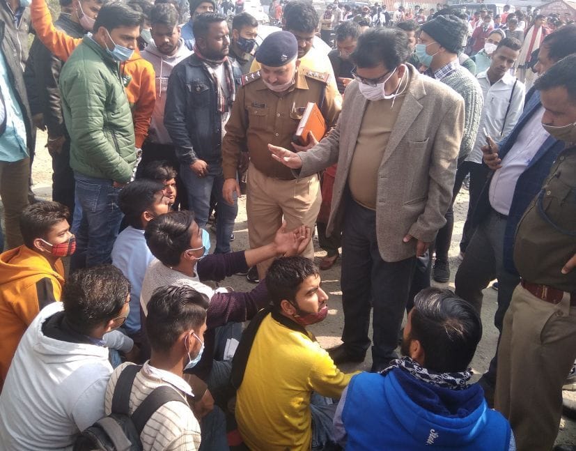 रुद्रपुर में कॉलेज गेट पर धरने पर बैठे छात्रों को समझाते प्राचार्य व कोतवाल।