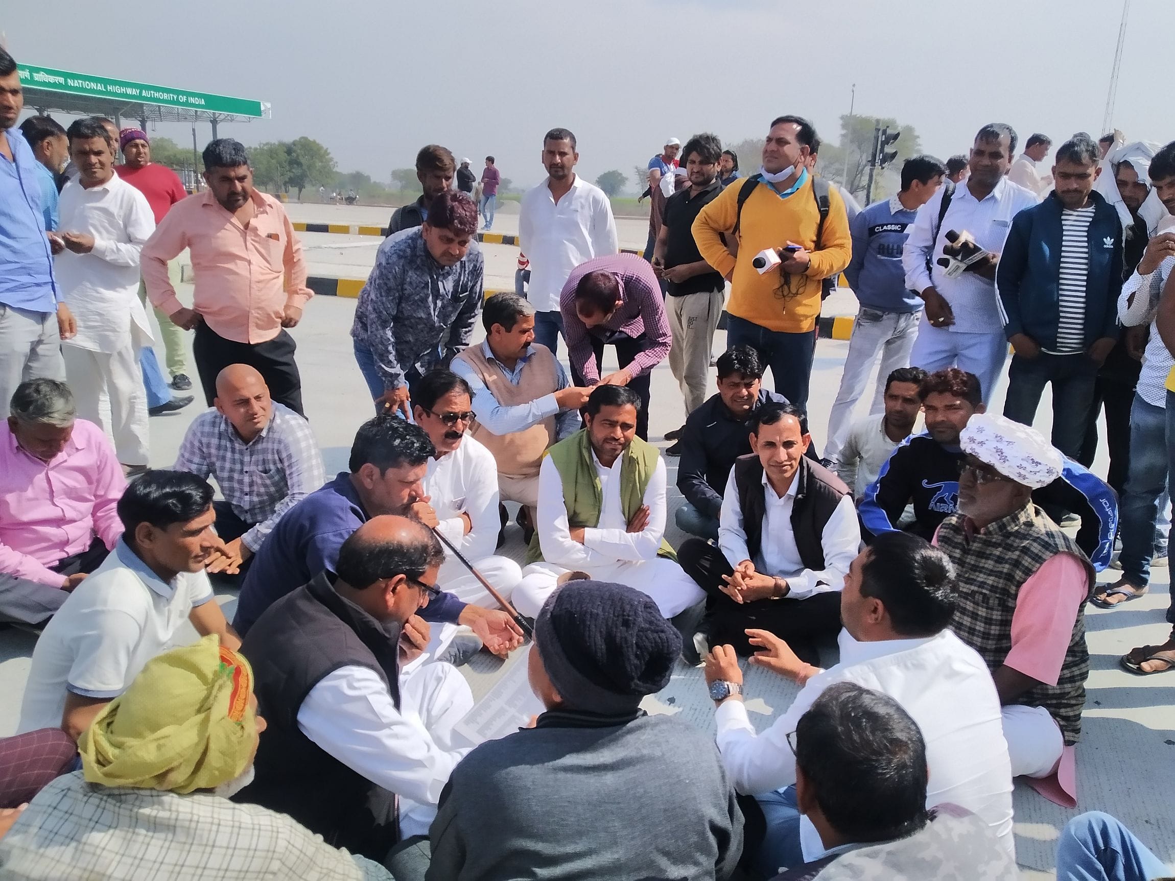 टोल प्लाजा पर बैठकर कर आगामी रूपरेखा बनाते ग्रामीण। संवाद टोल प्लाजा पर बैठकर कर आगामी रूपरेखा बनाते ग्रामीण। संवाद