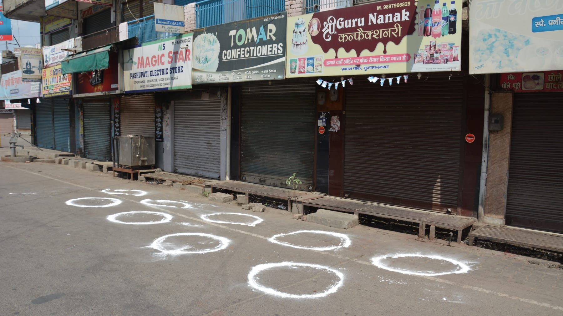 लॉकडाउन में सामाजिक दूरी के लिए दुकानों के आगे बनाये गये घेरे।
