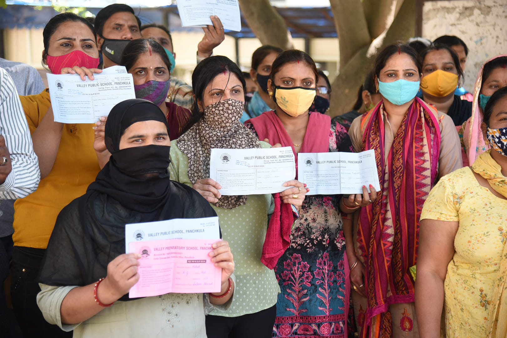 पेरेंट्स फीस स्लिप दिखाते हुए। 