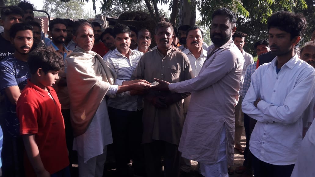 अग्निकांड पीड़ित को सहायता राशि देते ग्रामीण