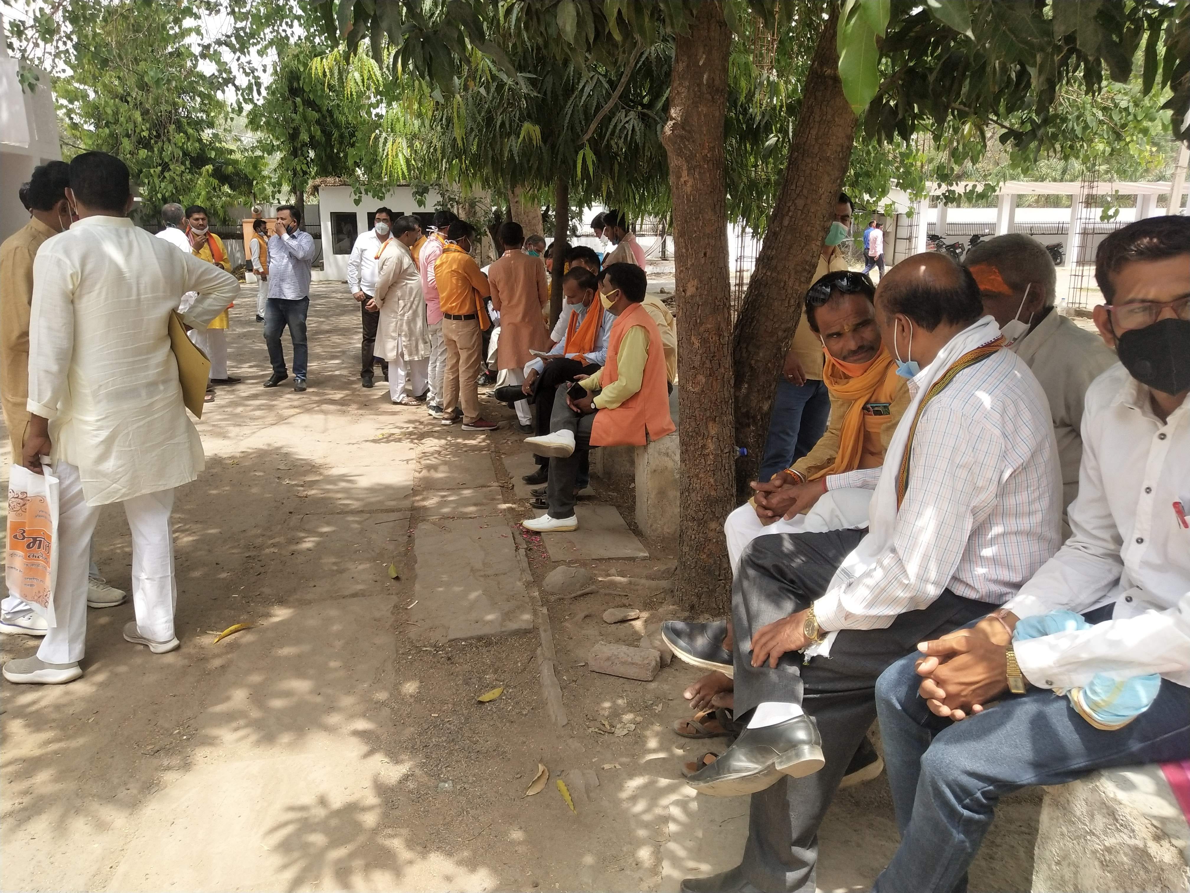 धूप के कारण कलेक्ट्रेट परिसर में वृक्ष के नीचे बैठे जिला पंचायत सदस्य पद के प्रत्याशी, प्रस्तावक 
