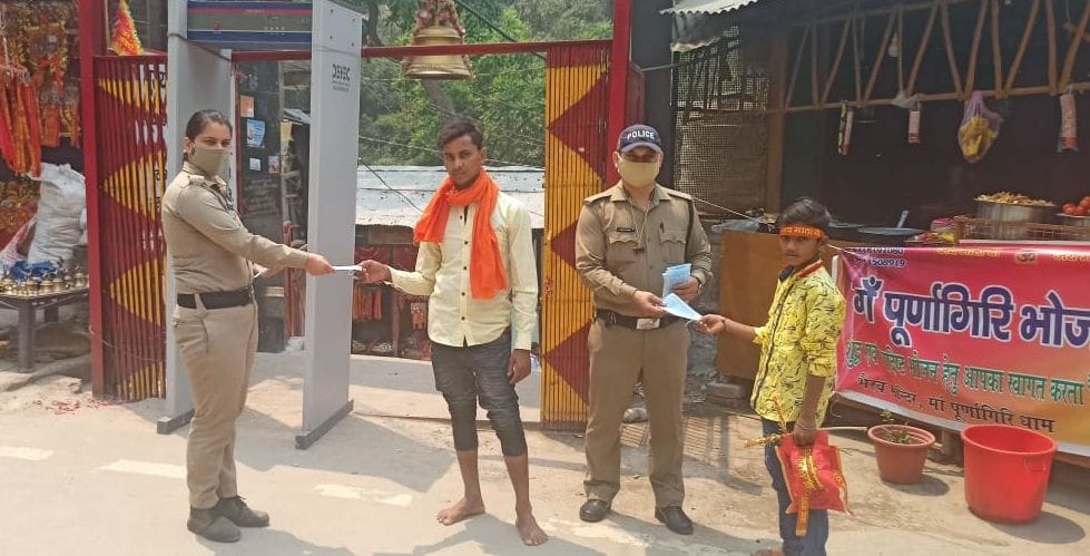 पूर्णागिरि मेले में श्रद्धालुओं को मास्क बांटते पुलिस कर्मी।