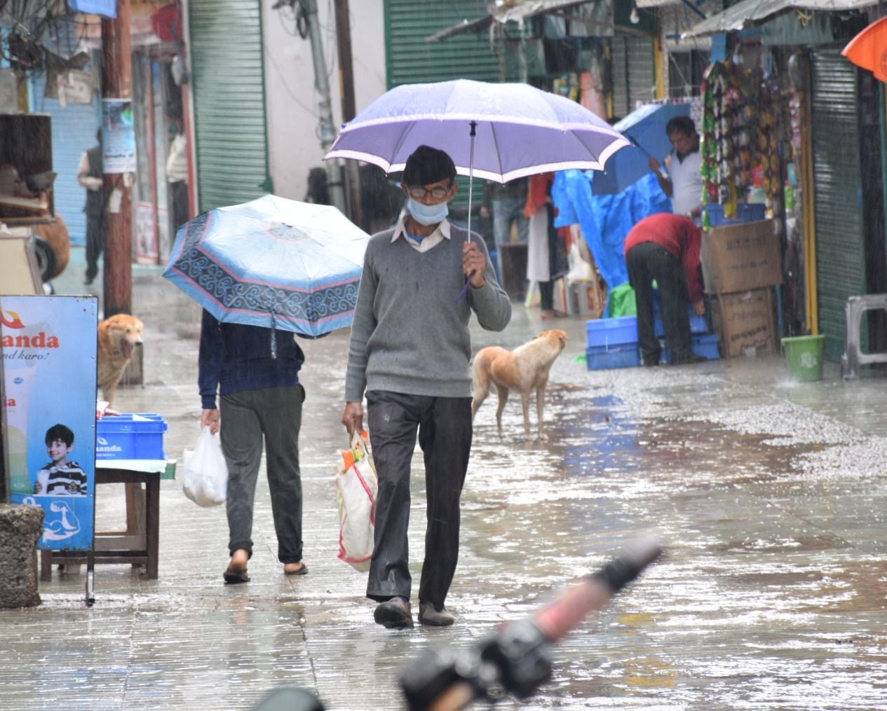 अल्मोड़ा में बारिश के दौरान छाता लेकर निकलते लोग।