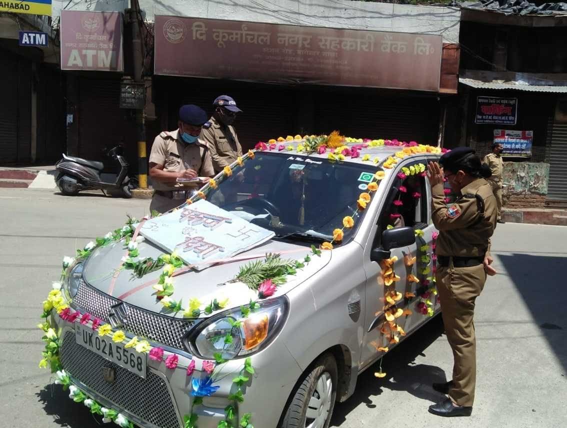 बागेश्वर में कर्फ्यू के दौरान अधिक सवारी बैठाने पर दूल्हे की कार का चालान काटते पुलिस कर्मी। संव?