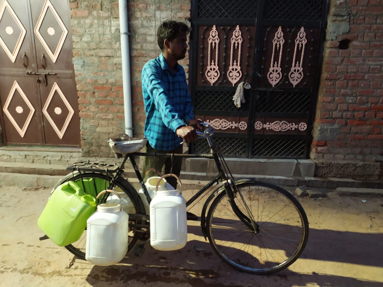 साइकिल पर प्लास्टिक कुप्पा के बांधकर पानी ढोता युवक साइकिल पर प्लास्टिक कुप्पा के बांधकर पानी ढोता युवक