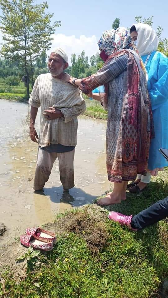 खेतों में काम कर रहे लोगों को वैक्सीनेशन करती कर्मचारी 